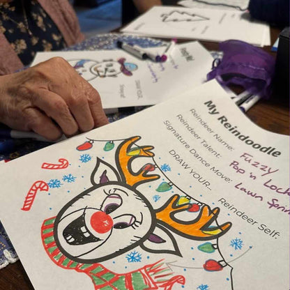 A festive reindeer coloring page titled My Reindoodle being filled in by grandma, featuring bright antlers, holiday lights, and prompts like Reindeer Name and Signature Dance Move. A joyful creative activity for all ages.